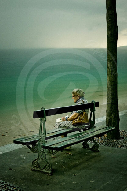 Photomontage d'une Vieille dame assise sur un ban dans Paris devant l'océan