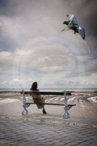 Photo-Montage Surréalisme Une femme assise sur un banc de Paris, devant l'immensité de l'océan