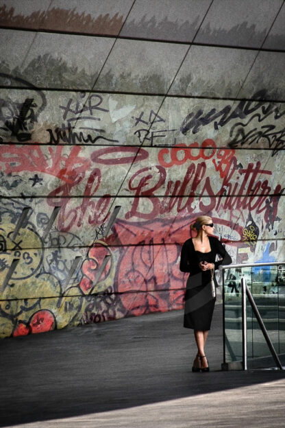 Photo Street-Art d'une femme belle et élégante, patientant devant un graffiti "The Bullshitters" porte Maillot
