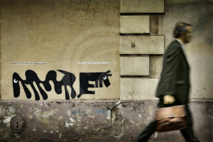 Photo Street-Art d'un cadre portant une sacoche et passant devant un graffiti